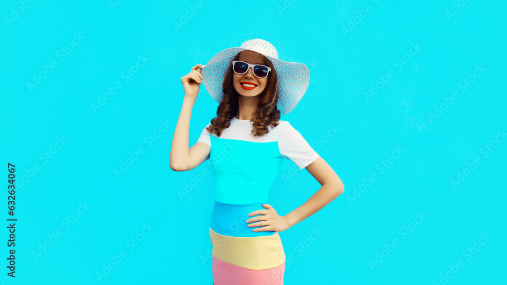 Beautiful young woman posing wearing summer straw hat, dress on blue studio background Beautiful young woman posing wearing summer straw hat, dress on blue studio background