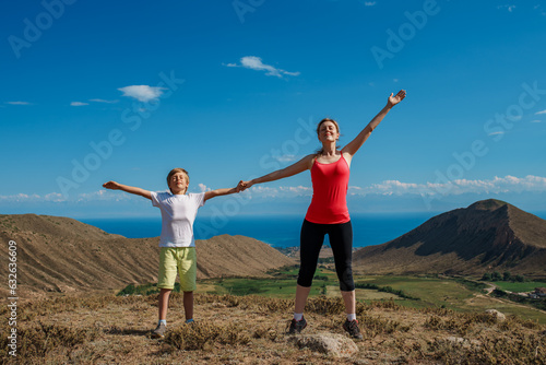 Happy mom and son stretching at the top of the mountain