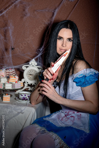 Halloween. Portrait of a young woman with a large kitchen knife. Dressed as Alice photo