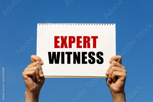Expert witness text on notebook paper held by 2 hands with isolated blue sky background. This message can be used as business concept about expert witness.