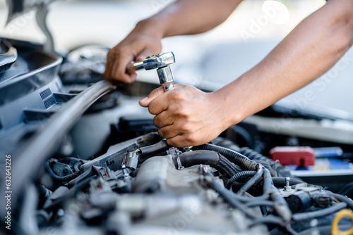 Auto mechanic repairman using a socket wrench working engine repair in the garage, changing spare parts, checking the mileage of the car, checking and maintenance service concept. photo