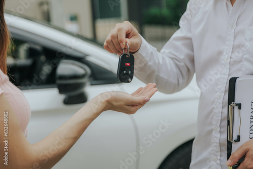 Automotive business, car sale or rental concept : Happy customer with car dealer agent making deal and signing on agreement document contract in auto showroom or car dealer office.