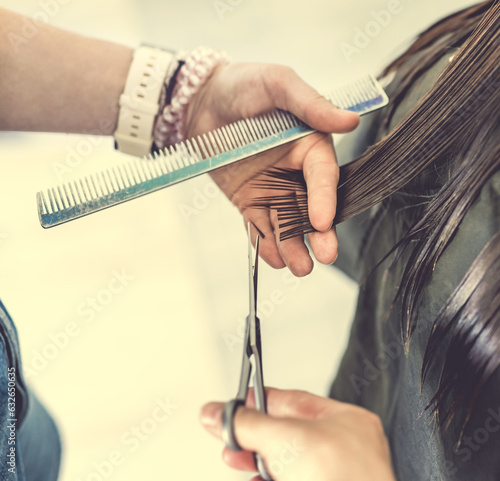 Hairdresser hands with scissors make hair cut in salon. Girl child during beauty routine in barbershop