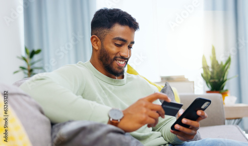 Credit card, finance and man with smartphone for online shopping in lounge at home. Indian, visa and money for e commerce transaction and search the internet for investment or product.