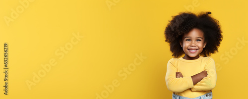 A first grader in a yellow jacket smiles and stands on a yellow background.