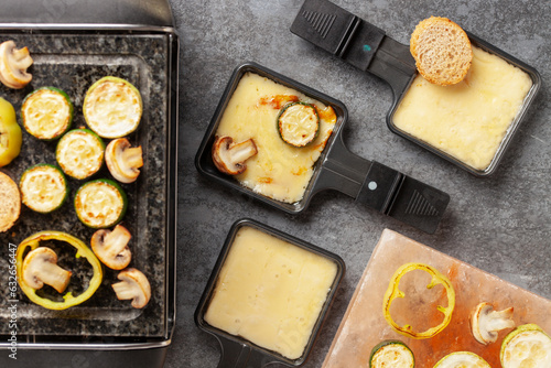 Photography Delicious traditional Swiss melted raclette cheese on diced boiled or baked vegetables served in individual skillets