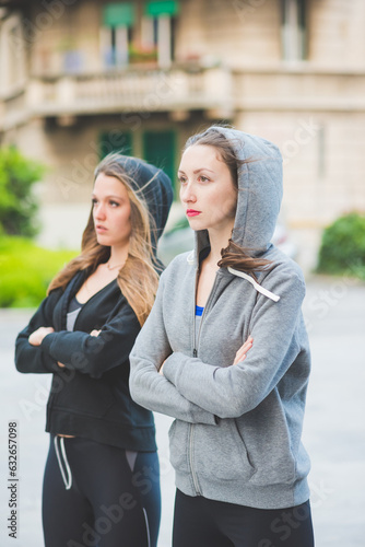 Two young millennial sportive woman wearing tracksuit arms crossed