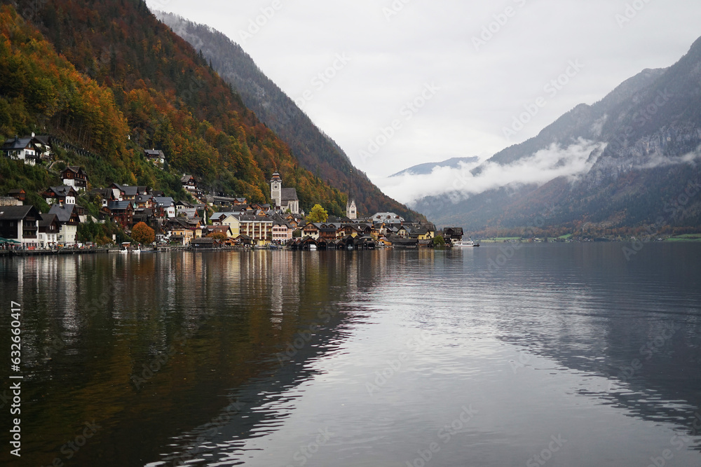 View of a small town with a church against the backdrop of mountains and a large lake on a cloudy autumn day 