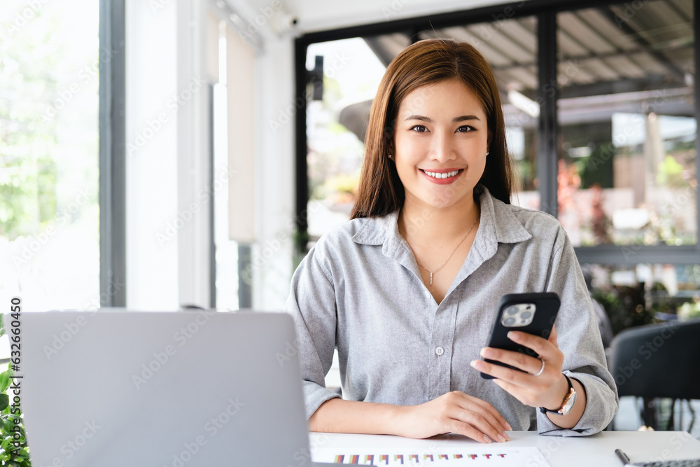 Asian woman in modern office working with laptop computer and holding mobile phone. Asian woman in modern office working with laptop computer and holding mobile phone.