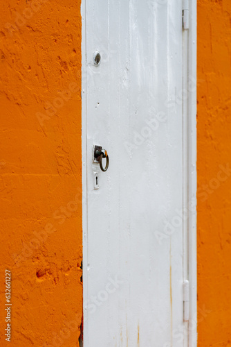 Orange and white painted door, closed with a handle and a keyhole