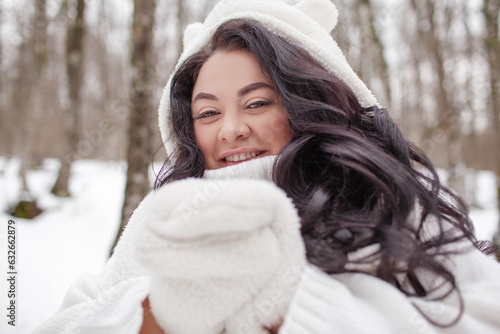 Beautiful woman wearing the white sweater, jeans and hat, the girl in warm cothes. Plus size woman waking, have fun in snow day