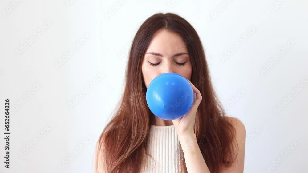 A beautiful woman inflates a blue balloon. A beautiful woman inflates a blue balloon.