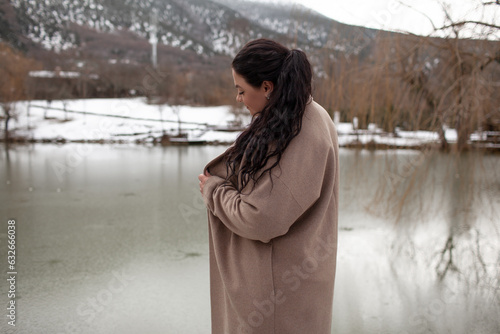 Beautiful woman wearing the coat, sweater and  jeans , the girl in warm cothes. Plus size  modelk waking in snow day in the winter nature photo