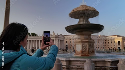 A girl photographs the fountain in St. Peter's Square in Rome in the Vatican City