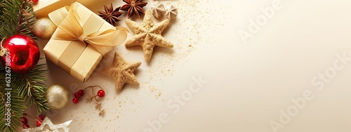 Christmas decoration composition on light gold background with beautiful Golden gift box with red ribbon, fir branches, cones, stars, Christmas cookies,cinnamon, top view, copy space, banner format