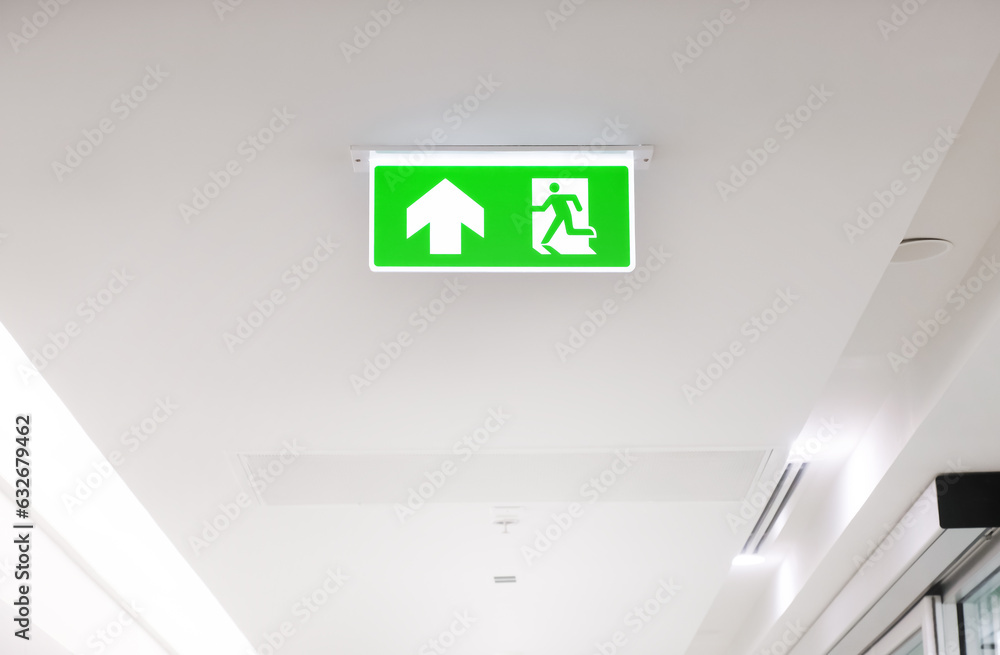 Exit Sign In Hall Lighted glowing green emergency exit signs in an office hallway with ...