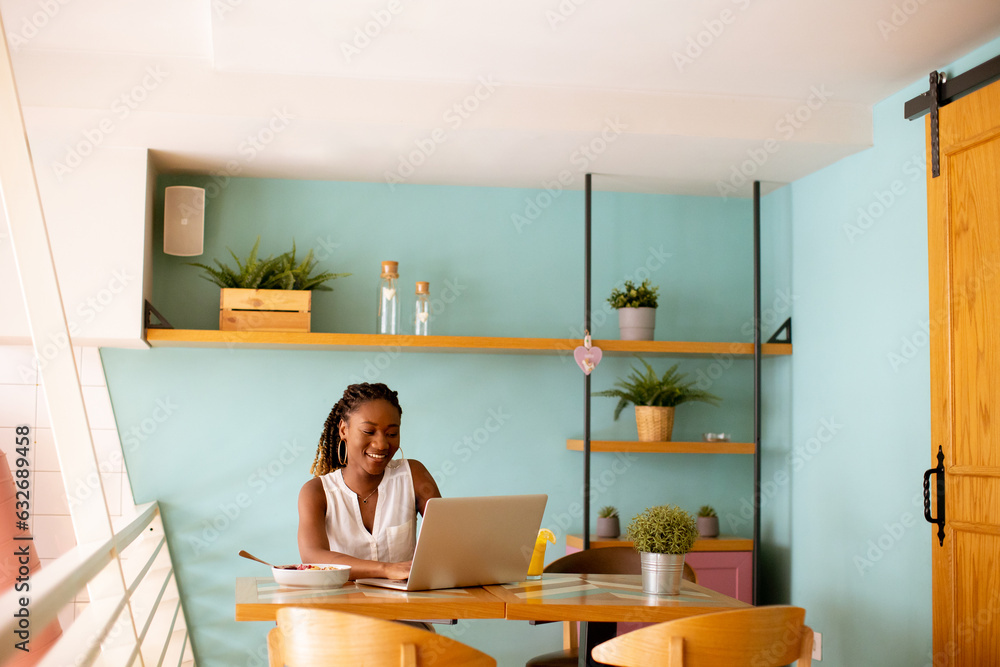 Young black woman drinking coffee while working on laptop in the cafe Young black woman drinking coffee while working on laptop in the cafe