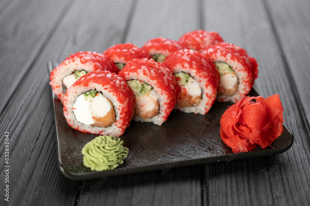Sushi rolls with masago caviar on black stone plate on wooden background, japanese food concept, sushi menu Sushi rolls with masago caviar on black stone plate on wooden background, japanese food concept, sushi menu