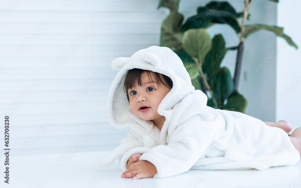 Adorable caucasian little baby daughter girl, wearing cute white bathrobe, taking bath in morning, sitting in baby bathtub, laughing, smiling with happiness at home or house. Kid Development Concept Adorable caucasian little baby daughter girl, wearing cute white bathrobe, taking bath in morning, sitting in baby bathtub, laughing, smiling with happiness at home or house. Kid Development Concept