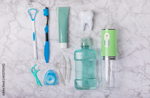 Electronic oral irrigator, toothbrush, paste, dental floss and mouthwash on marble background. Dental tool for oral hygiene. Electric Interdental Cleaner. Dental water shower. Oral care concept. 