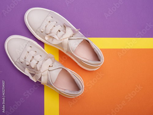 A close-up view of comfortable casual beige sneakers on a three-colored background. Shoe advertising concept