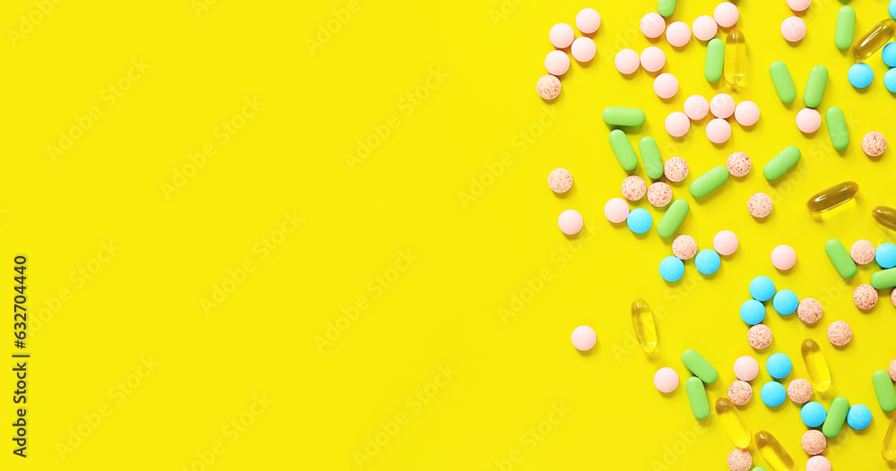 Vitamins of different colors on a yellow background. Top view of scattered bright pills. Pharmaceutical industry. Health care and medicine. Pharmacy product. Banner with place for text. Copy space