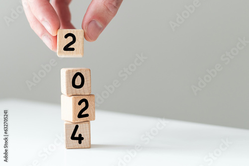 2024 Happy New year background banner. Two thousand Twenty-Three year numbers on wooden cube blocks stack on white background with copy space. Welcome, Merry Christmas, and Happy New Year in 2023.