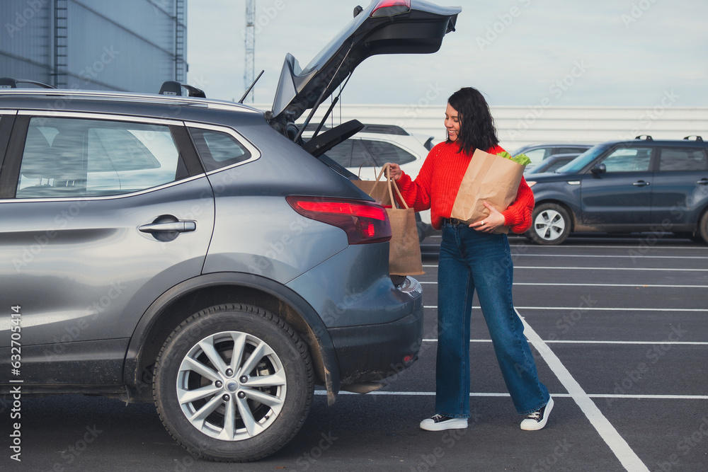 smiling woman put bags in car trunk smiling woman put bags in car trunk