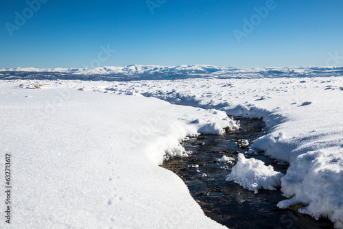 a small river winds its way through a snow covered steppe landscape