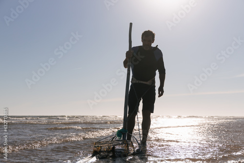 фотографія Serious man with dragnet fishing clam shells in sea