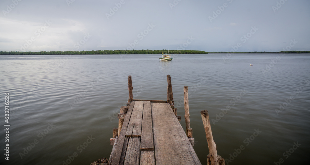 fishing boat waiting in front of wooden pier in clouded day