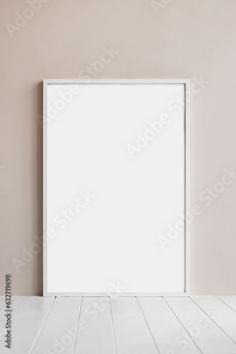 Blank picture frame mockup on white wall. View of scandinavian style interior with artwork mock up standing on wooden floor. Modern living room design