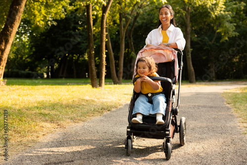 Japanese Mom Walking With Toddler Daughter In Stroller At Park photo