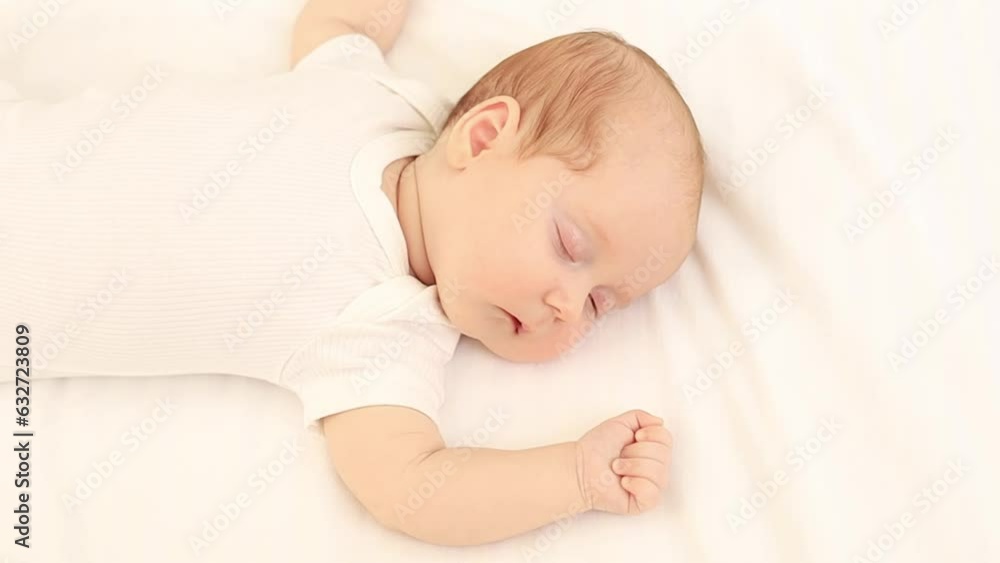 a newborn baby sleeps in a white bodysuit on a cotton bed at home, close-up portrait, space for text a newborn baby sleeps in a white bodysuit on a cotton bed at home, close-up portrait, space for text