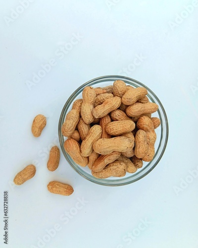 Roasted salted peanuts in glass bowl isolated on white background