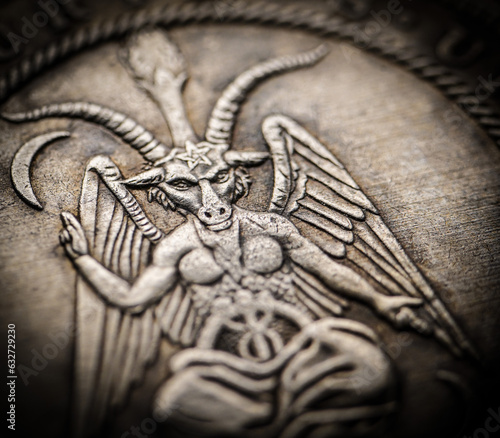 Closeup of hobo coin with Baphomet carved on it's metal surface with focus on face.
