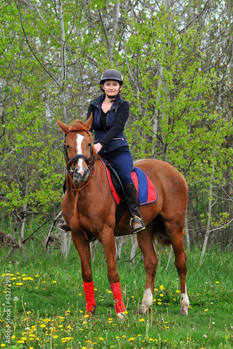 A jockey girl rides a horse on a green meadow © Mykola