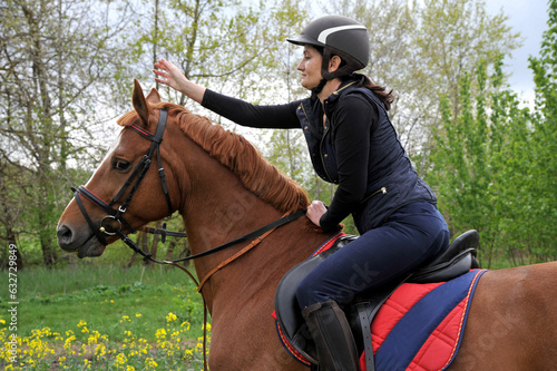 A jockey girl rides a horse on a green meadow