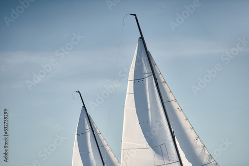 the tops of several sails are illuminated by the sun at sunset, clear sky, masts © Vladimir Drozdin