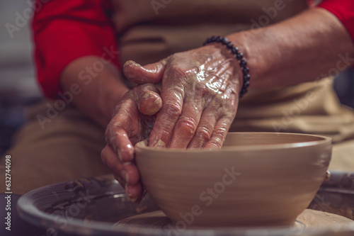 Ceramic plate on a potter's wheel, ceramist's hands.