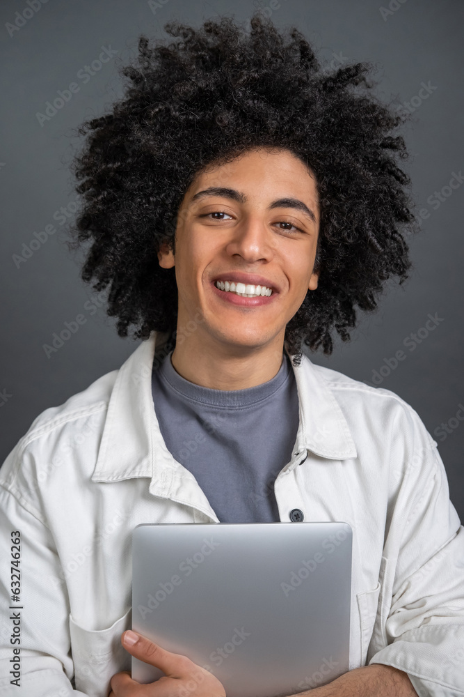 Young curly-haired digital nomad with a laptop in hands smiling Young curly-haired digital nomad with a laptop in hands smiling