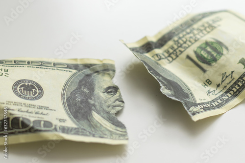 a hundred dollar bill torn in half on a white background top view