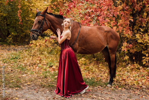 Female portrait next to a horse. Horseback riding in the autumn forest