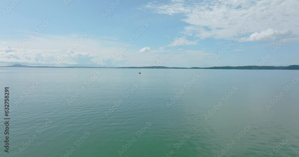 Aerial: Lone sailing boat in the ocean on a calm day. Auckland, New Zealand Aerial: Lone sailing boat in the ocean on a calm day. Auckland, New Zealand