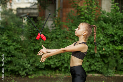 Rhythmic gymnastics. Preteen child exercising with gymnastic mace outdoor. Healthcare concept