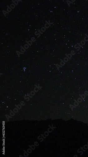 A view of the stars of the Milky Way with a mountain top in the foreground. Night sky nature summer landscape. Perseid Meteor Shower observation. Vertical video for social media. photo