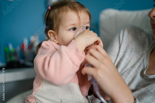one toddler girl and mother using steam inhaler nebulizer at home