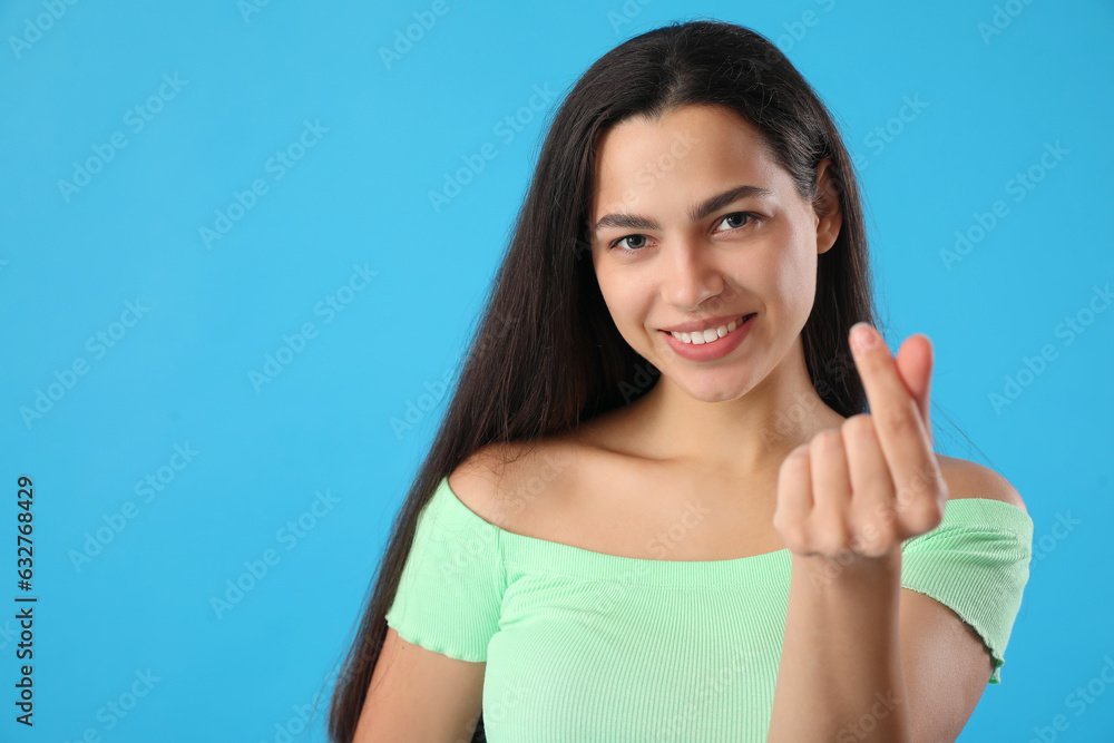 Beautiful young woman making heart with her fingers on blue background, closeup Beautiful young woman making heart with her fingers on blue background, closeup