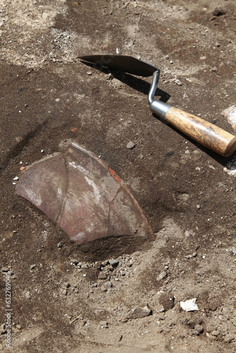 Authentic archaeological excavation with excavated clay shard, a real artefact an an excavation trowel