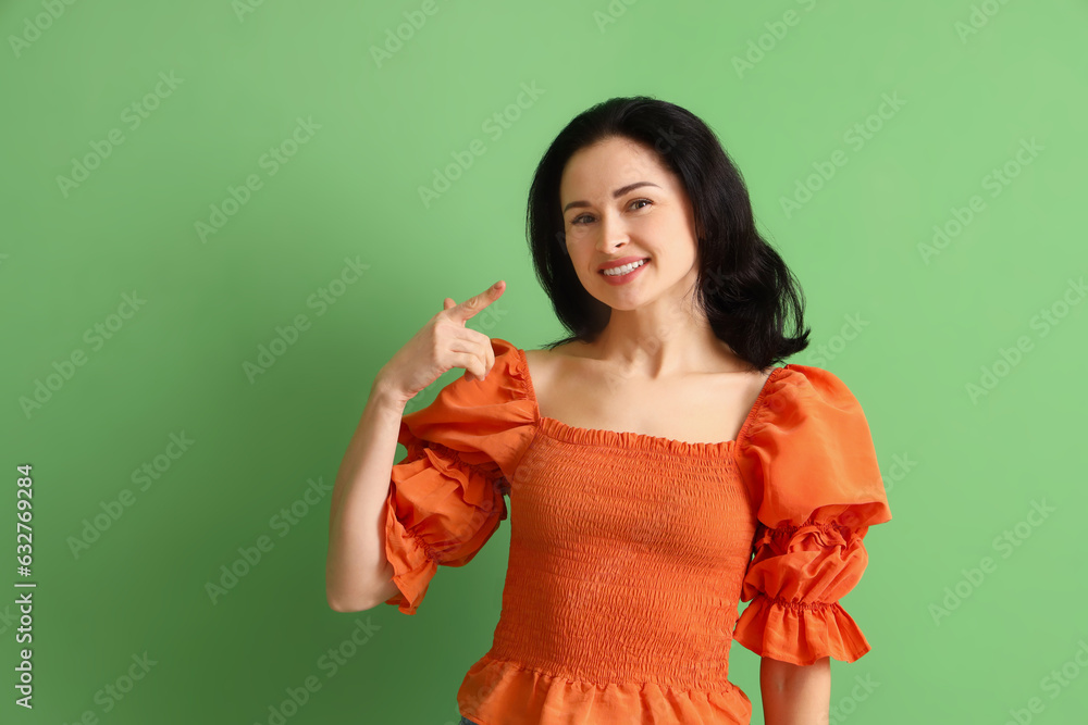 Beautiful woman pointing at her smile on green background Beautiful woman pointing at her smile on green background